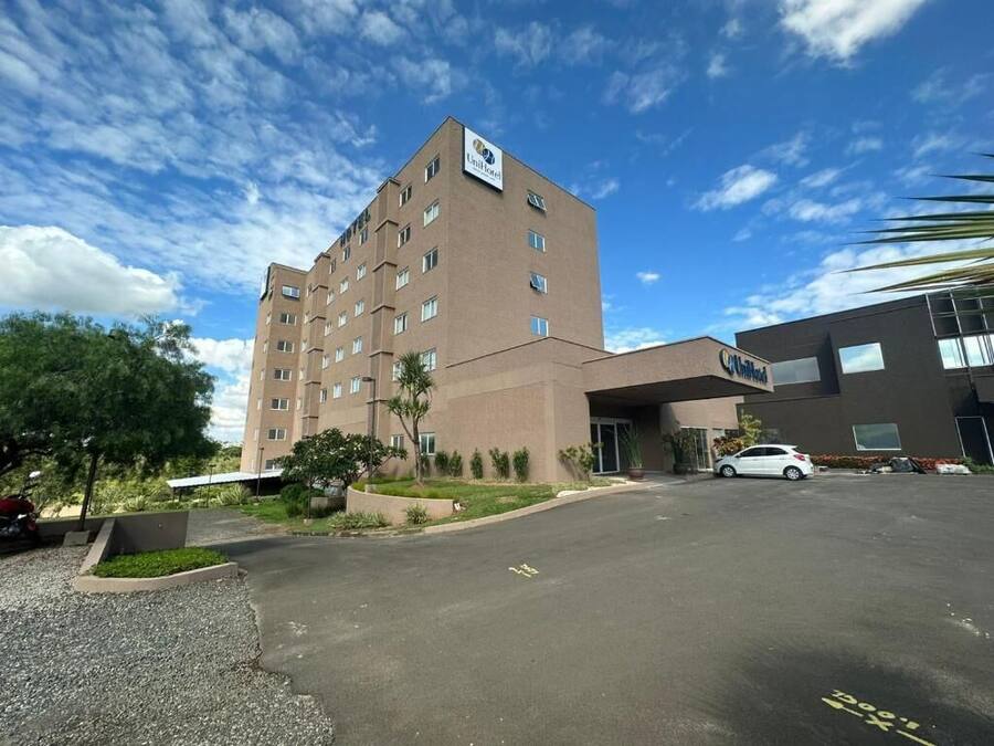 Ein Hotel mit modernem Design, das einen großen Parkplatz und ein mehrgeschossiges Gebäude bietet.