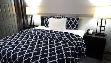 A neatly made bed with a patterned bedspread, a white pillow, and two bedside tables with lamps and a phone.