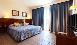 A hotel room with a bed, a desk with a television, and two wall-mounted lamps. - Hotel Rambla Benidorm (Benidorm)