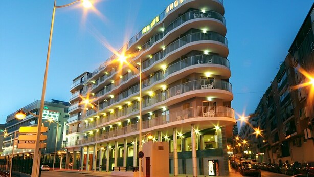 Un hôtel à plusieurs étages, doté d’une façade incurvée, de balcons et d’une entrée au niveau du sol.