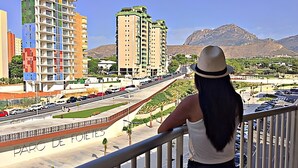 Une personne qui contemple un paysage urbain avec des bâtiments modernes et une chaîne de montagnes en arrière-plan.