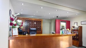 Un comptoir d’accueil en bois, un fauteuil de bureau noir, un tableau d’affichage et un distributeur automatique.