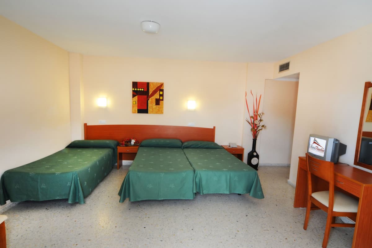 A hotel room with two single beds, a wooden desk, a chair, a television, and a wall-mounted artwork.