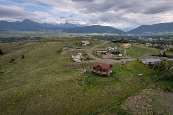 A rural village with houses and a winding road, surrounded by mountains. - Goat Mountain Cabin: Mountain Views & Big Sky Comfort in Livingston (Livingston)