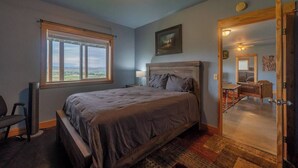 A bedroom with a large bed, a window with a view, a desk, and a chair. - Goat Mountain Cabin: Mountain Views & Big Sky Comfort in Livingston (Livingston)