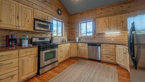 A modern kitchen with wooden paneling, stainless steel appliances, and a skylight. - Goat Mountain Cabin: Mountain Views & Big Sky Comfort in Livingston (Livingston)
