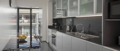 Une cuisine moderne dotée d’un plan de travail noir, d’appareils électroménagers en acier inoxydable et d’un meuble avec une porte en verre.