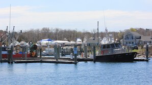Un port de plaisance avec des bateaux amarrés, un bateau pilote et une maison en arrière-plan.