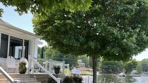 Une maison dotée d’une terrasse en bois, d’un espace salon extérieur et offrant une vue sur un lac.