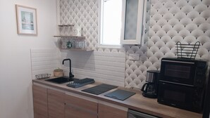 Eine moderne Küche mit Holzarbeitsplatte, einer schwarzen Kaffeemaschine, einem schwarzen Backofen und einem Waschbecken mit schwarzem Wasserhahn.