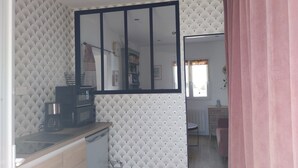 Eine kompakte Küche mit modernem Design, ausgestattet mit einer eingebauten Mikrowelle, einer Kaffeemaschine und einem kleinen Spülbecken.