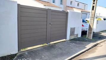 A gated residential area with a white wall and a brown gate.