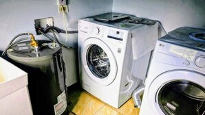 Un área de lavandería con lavadora, secadora y un calentador de agua grande.
