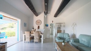Ein geräumiges Wohnzimmer mit Essbereich, einer Couch, einem Couchtisch und einem Chandelier.