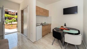 Una cocina compacta con refrigerador, armarios de madera y una zona de comedor con mesa y sillas.