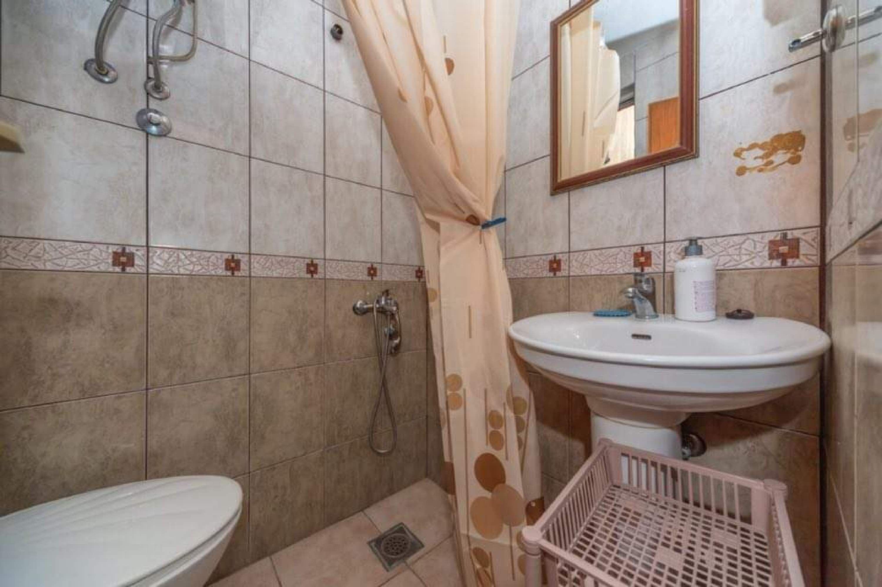 A bathroom with a toilet, sink, shower, and a mirror.