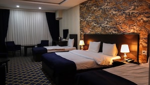 A hotel room with two beds, a desk, and a chair.