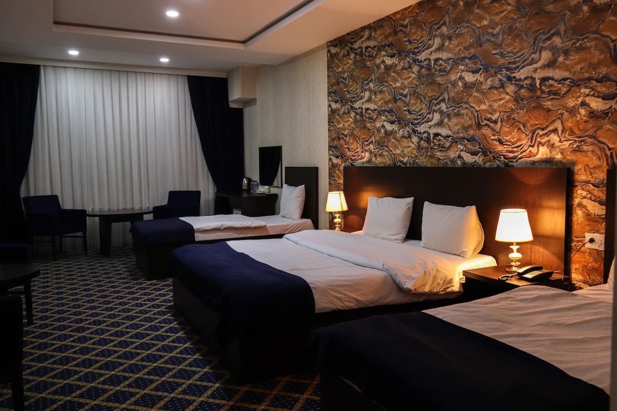Une chambre d’hôtel avec deux lits, un bureau et une chaise.
