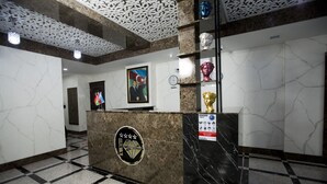 A reception area with a marble counter, a framed portrait, and a bust on display.