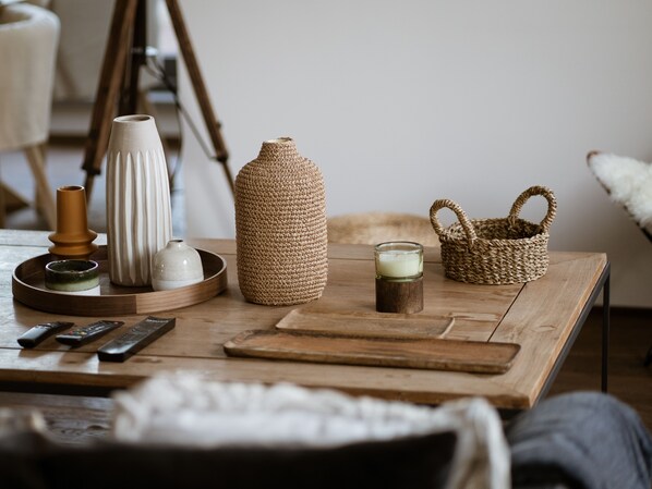 A wooden table with various items including a woven basket, a candle, and remote controls. - Experience Rome’s grandeur from our Skylife Penthouse with 360° views of Tiber (Roma)