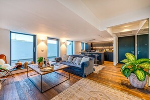 A modern living room with a sofa, coffee table, and large windows.