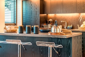 A modern kitchen with a marble countertop, stainless steel appliances, and a wooden backsplash.