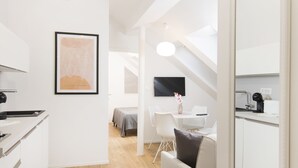Een modern, goed verlicht appartement met een kitchenette, een eetgedeelte en een woonruimte.