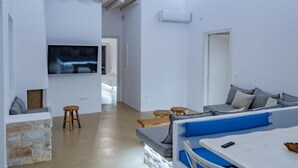 Una sala de estar moderna con un sofá, un televisor y un comedor con una mesa y sillas.