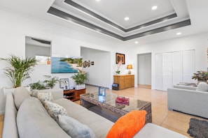 A modern living room with a sofa, coffee table, and a view of the sea through an open doorway.