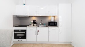 A modern kitchen with white cabinets, a Bosch oven, a microwave, and a sink. - Family-Friendly 1BR Retreat w/ Pool & Beach Access (Noord)