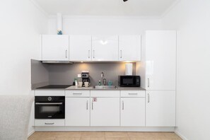 A modern kitchen with white cabinets, a Bosch oven, a microwave, and a sink. - Family-Friendly 1BR Retreat w/ Pool & Beach Access (Noord)