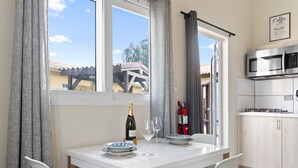 A dining area with a table set for two, a bottle of champagne, and two wine glasses. - Cozy one-bedroom apartment in Little Sea (Noord)