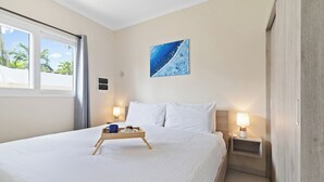 Habitación de hotel con una cama grande, una mesita de noche, una lámpara de noche, una ventana con cortinas y un cuadro en la pared.