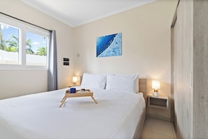 Una camera d'albergo con un letto grande, un comodino, una lampada da letto, una finestra con tende e un quadro appeso al muro.