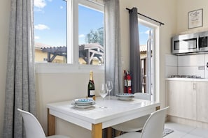 Un coin repas avec une table dressée pour deux personnes, une bouteille de champagne et deux verres à vin.