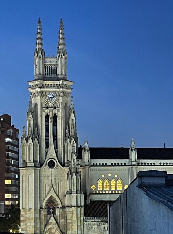 A Gothic-style church with a tall spire and a clock. - Hotel Lourdes 62 (Bogotá)