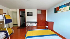 A hotel room with a bed, a desk, a chair, a wardrobe, and a television. - Hotel Lourdes 62 (Bogotá)
