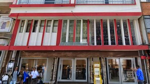 A multi-story building with a red and white facade, large windows, and a ground-level entrance with glass doors. - Hotel Lourdes 62 (Bogotá)