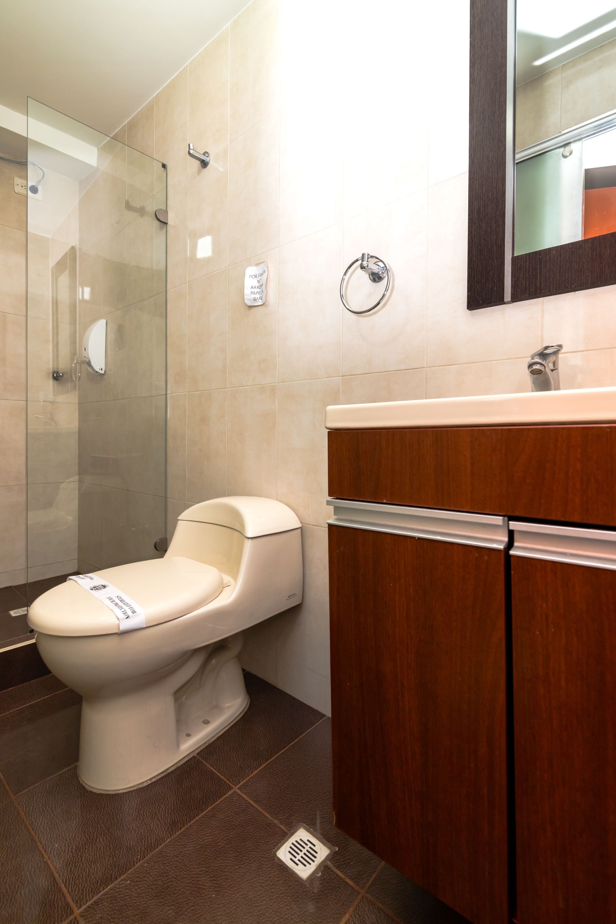 Une salle de bain moderne équipée de toilettes, d’une douche et d’un meuble-lavabo avec un miroir.