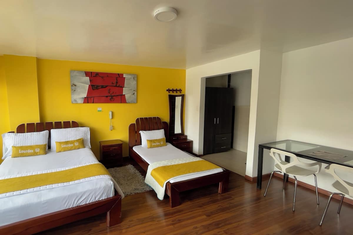 Una habitación de hotel con dos camas, un escritorio, un armario y un espejo.