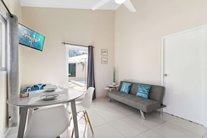 Ein modernes Wohnzimmer mit Esstisch, Sofa und einem an der Wand befestigten Fernseher.