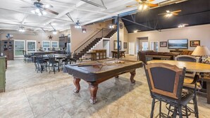 A spacious living area with a pool table, dining area, and a staircase leading to an upper level. - Family Getaway on the River | Pool, Sleeps 15, Spacious (Brazoria)