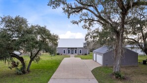 A single-story building with a concrete driveway leading to a front door. - Family Getaway on the River | Pool, Sleeps 15, Spacious (Brazoria)