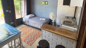 A compact room with a bed, a small kitchenette, a table, and a fan. - POSADA MISS ANIBEL  (San Andrés)