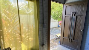 A room with a concrete floor, a green curtain, a wooden door, and a patterned rug. - POSADA MISS ANIBEL  (San Andrés)