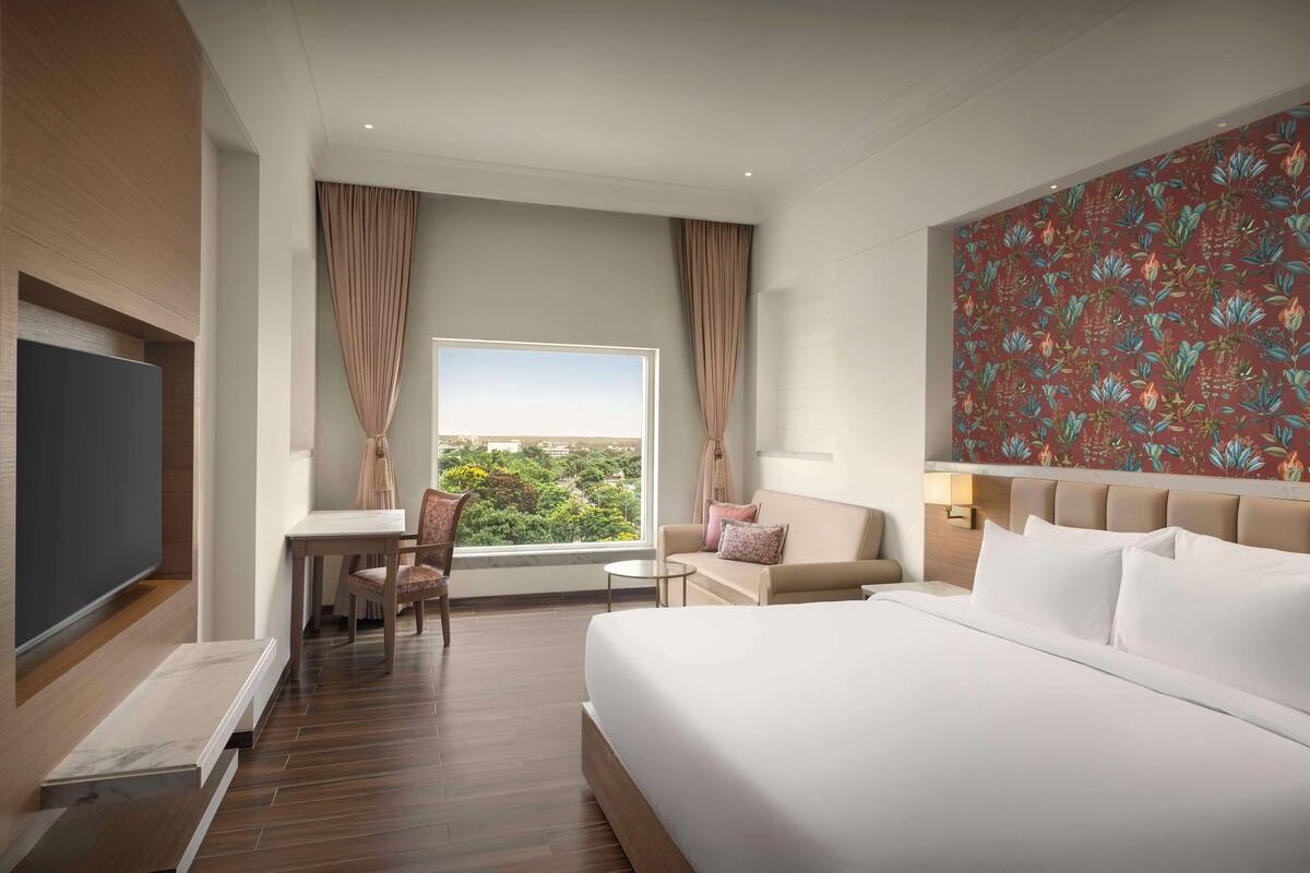 Une chambre d’hôtel avec un grand lit, un bureau, une chaise et une vue sur la ville.