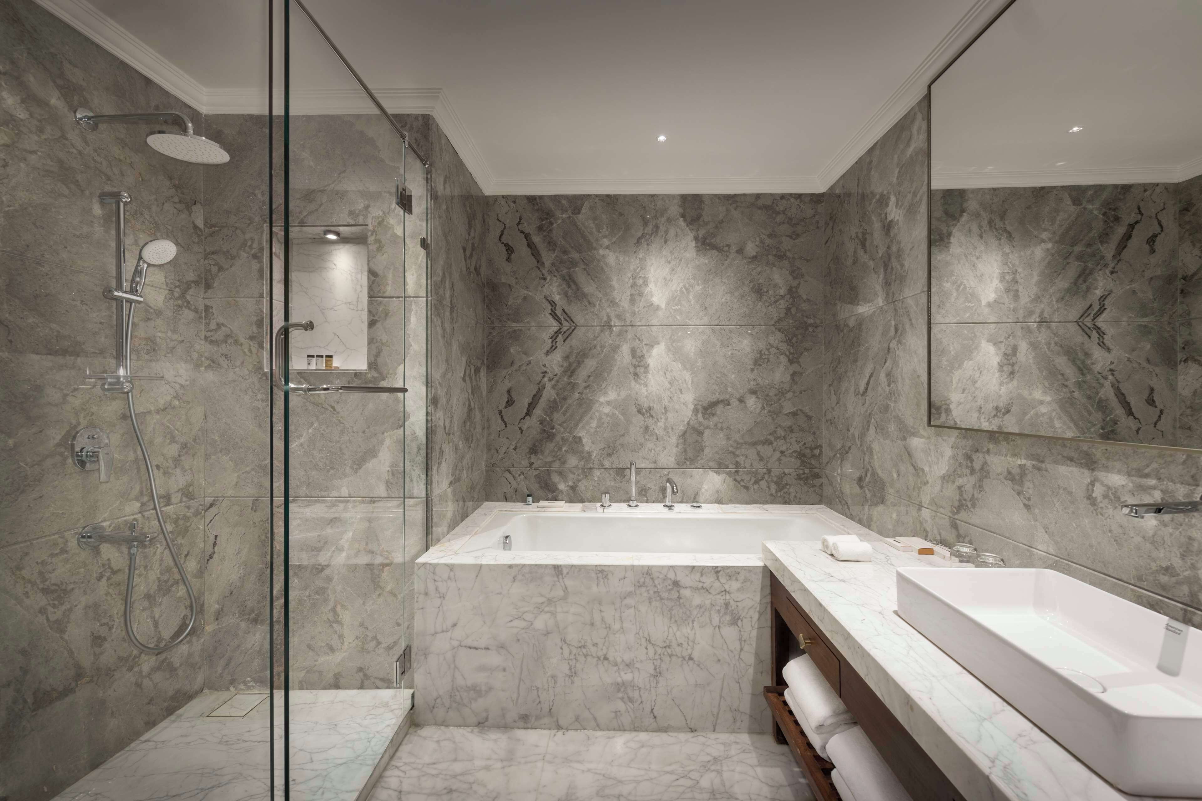 A modern bathroom with a glass-enclosed shower, a freestanding bathtub, and a large vanity with a sink.