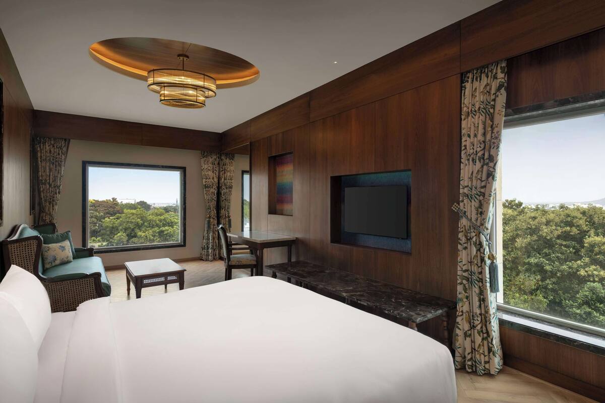 Une chambre d’hôtel moderne dotée d’un grand lit, d’un coin salon avec une table et d’un téléviseur fixé au mur.
