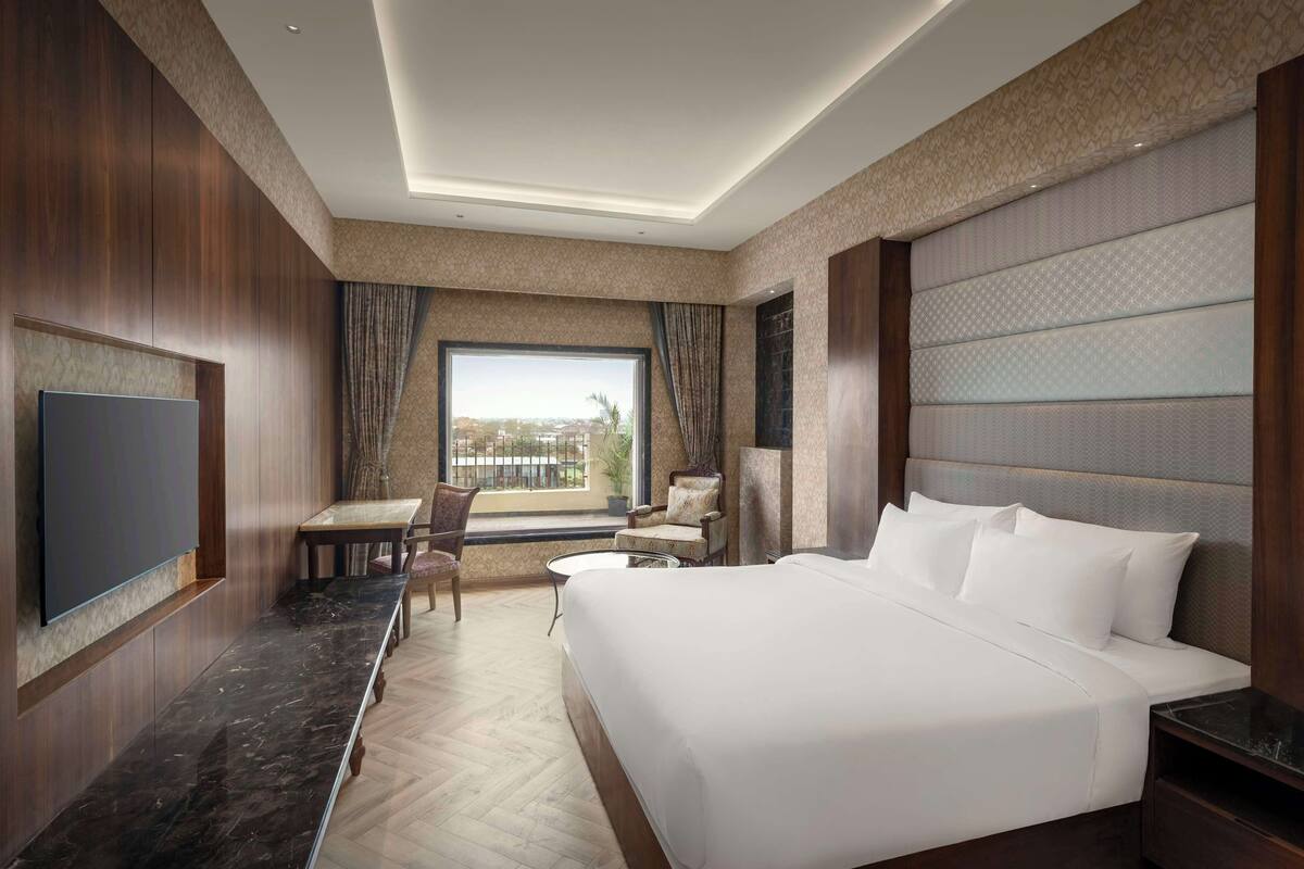 Une chambre d’hôtel dotée d’un grand lit, d’un téléviseur à écran plat, d’une table à manger et offrant une vue sur l’extérieur.