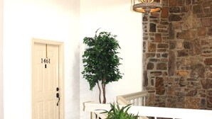A hallway with a stone wall, a white door with a number, a potted plant, and a hanging light fixture. - Lake Views from this Balcony are amazing! (Hot Springs)